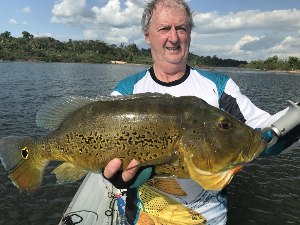 amigo mostrando o peixe tucunaré que ele pescou no rio Xingu