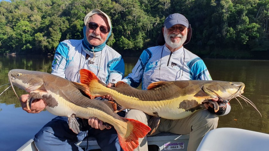 dois pescadores mostrando as pirararas que pegaram