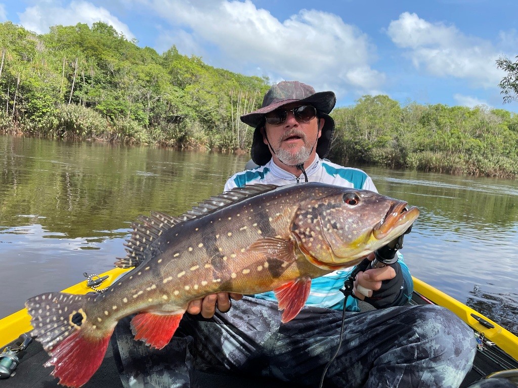 Angler in a cap showing a beautiful peacock bass he caught on Amazon Xplor
