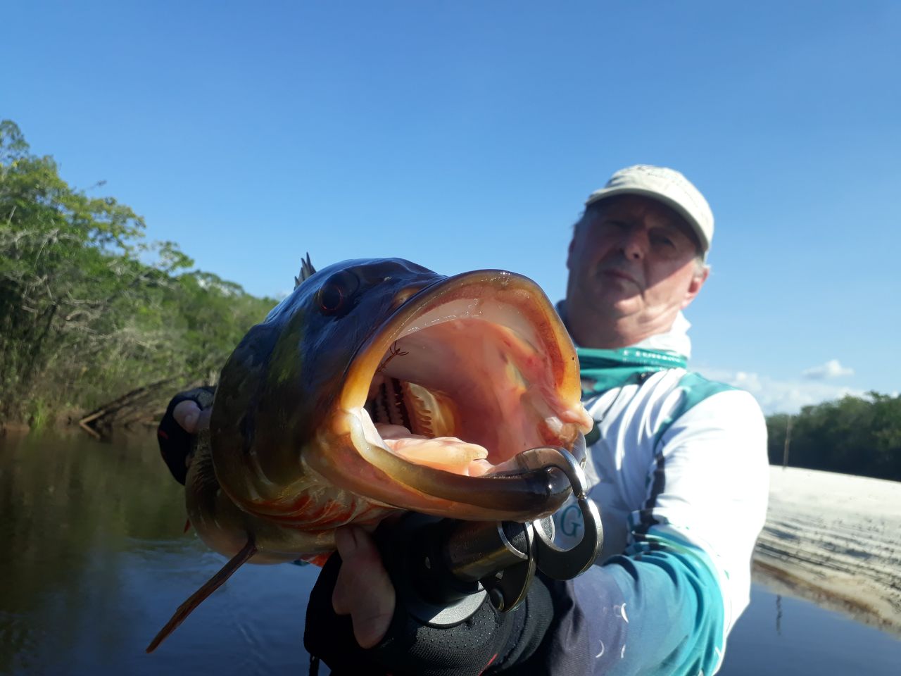 Fisherman showing a tucunare with its big mouth open