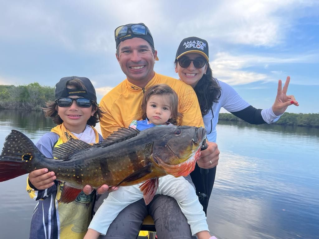 Family on a boat showing a beautiful peacok bass caught on Amazon Xplor